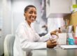 Woman pharmacist sitting at her desk smiling.